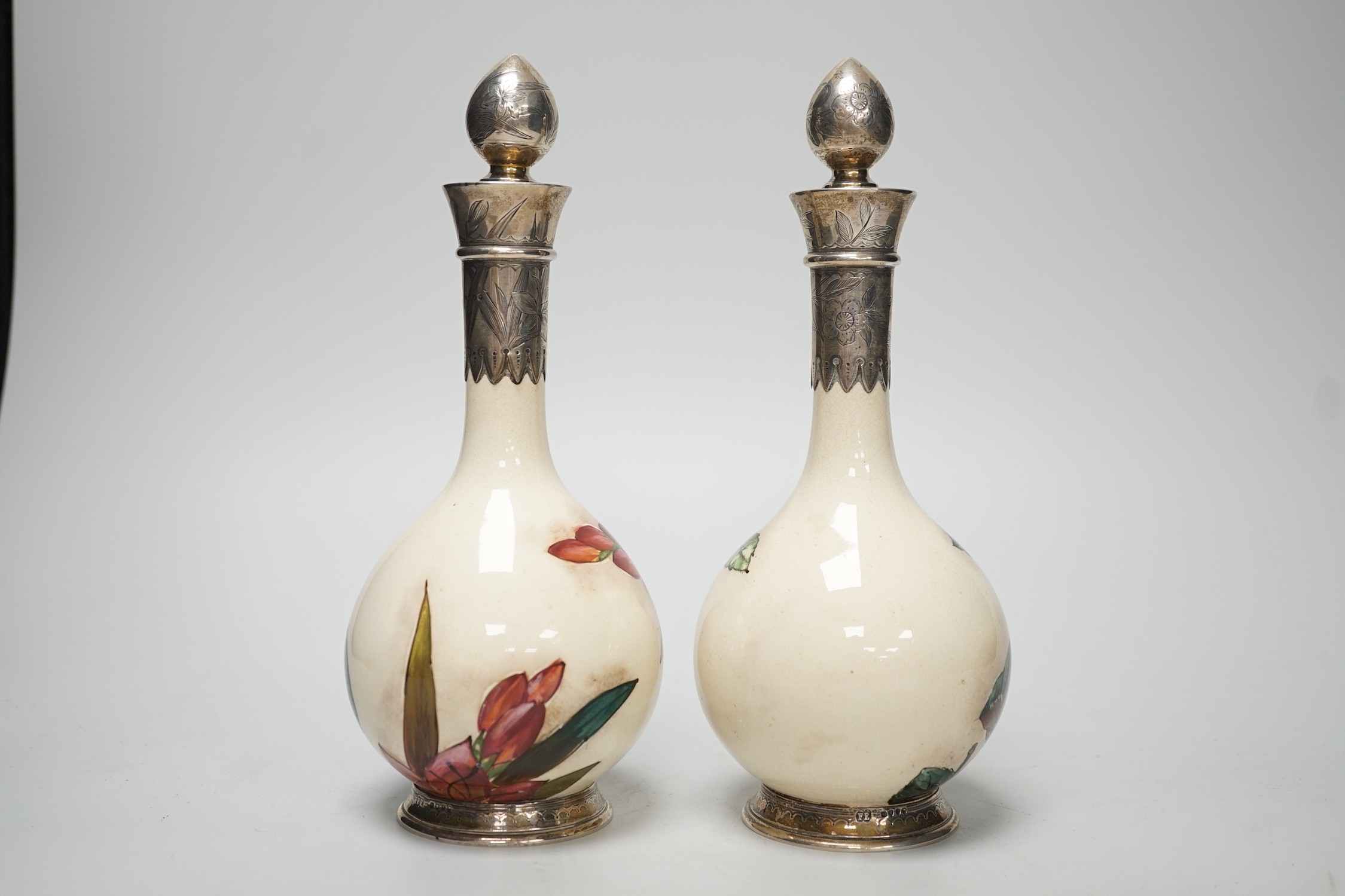 A pair of Victorian silver mounted floral painted earthenware bottle vases. 21cm high